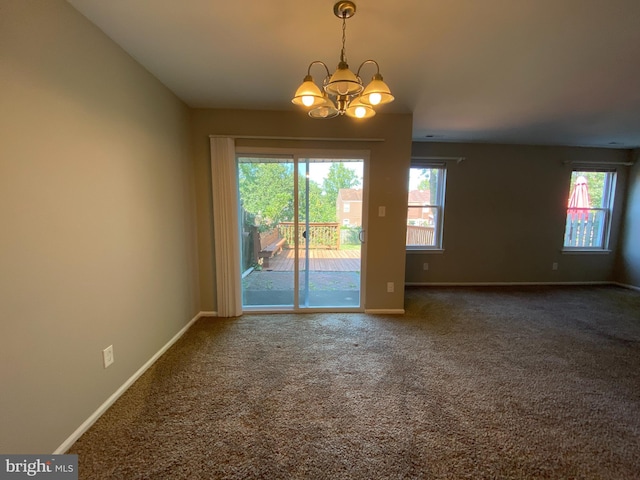 carpeted spare room with an inviting chandelier