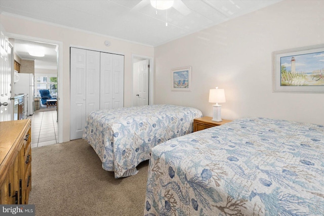 tiled bedroom featuring crown molding, ceiling fan, white refrigerator, and a closet