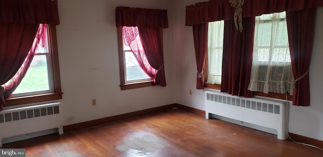 empty room featuring radiator and hardwood / wood-style flooring