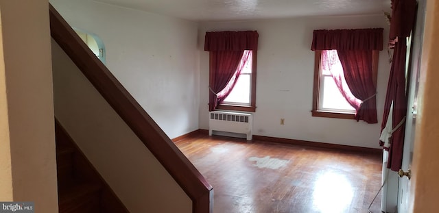 empty room with radiator heating unit and light hardwood / wood-style flooring