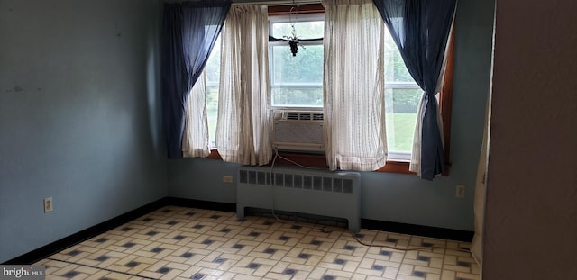 empty room with a healthy amount of sunlight, radiator heating unit, and cooling unit