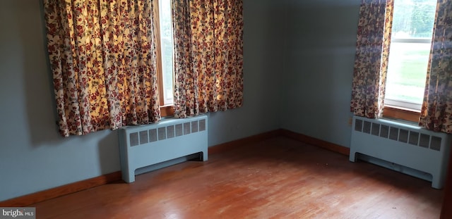 empty room with radiator and hardwood / wood-style floors