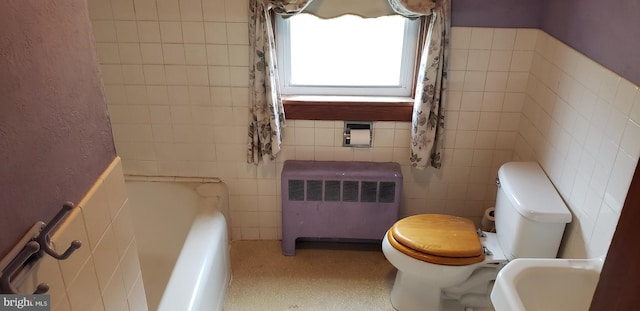 bathroom featuring tile walls, radiator, a tub, and toilet