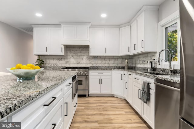 kitchen with white cabinets, light stone counters, sink, and appliances with stainless steel finishes