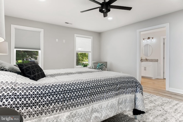 bedroom featuring ensuite bathroom, ceiling fan, and light wood-type flooring