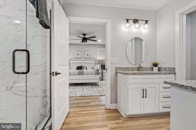 bathroom with hardwood / wood-style flooring, ceiling fan, a shower with shower door, and vanity