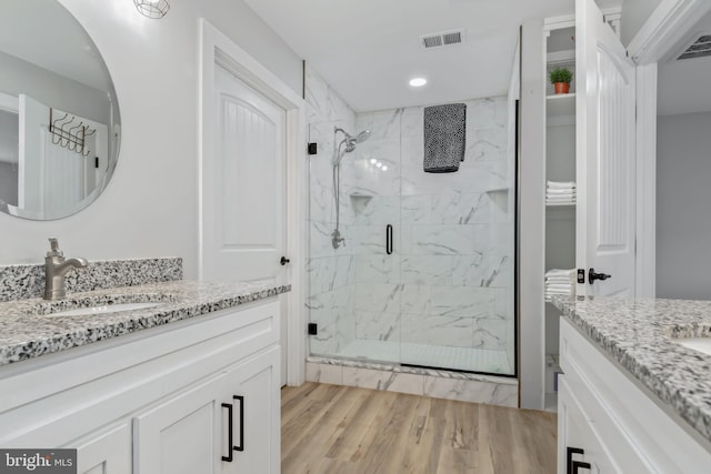 bathroom with wood-type flooring, vanity, and a shower with shower door