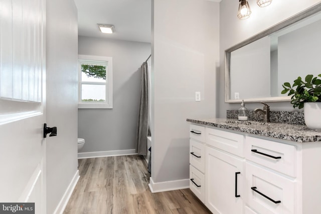 full bathroom featuring vanity, toilet, wood-type flooring, and shower / tub combo with curtain