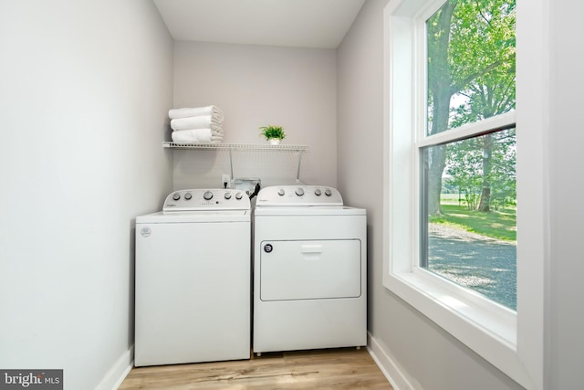 laundry room featuring light wood-type flooring, a wealth of natural light, and washing machine and clothes dryer