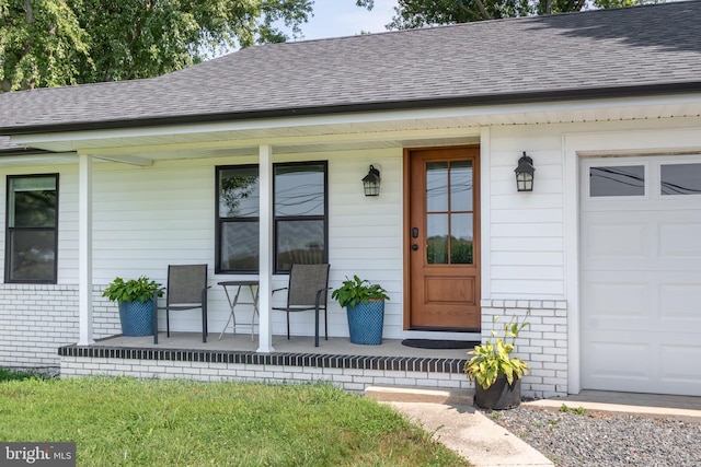 view of exterior entry featuring a porch and a garage