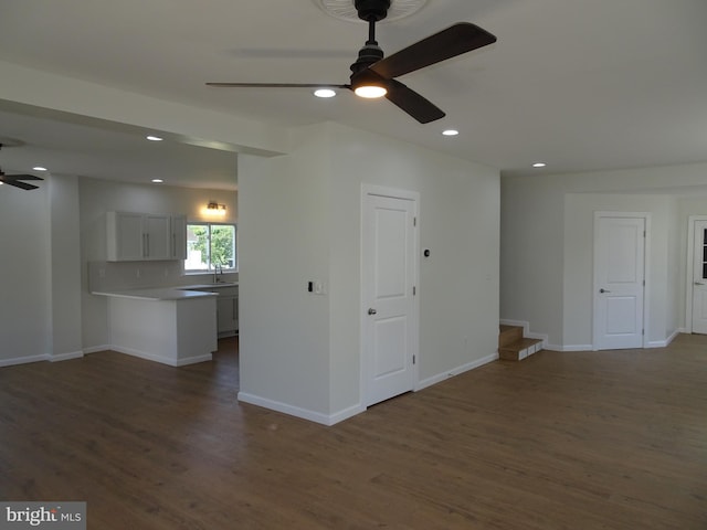 empty room featuring ceiling fan, recessed lighting, a sink, baseboards, and dark wood finished floors