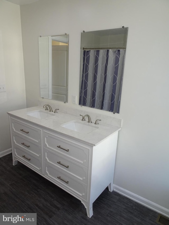 full bathroom featuring double vanity, visible vents, a sink, and wood finished floors