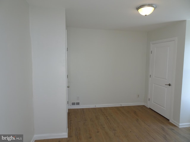 spare room featuring light wood finished floors, visible vents, and baseboards