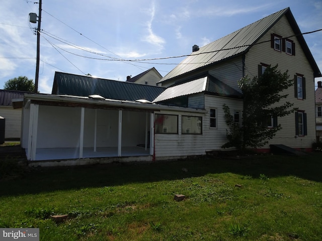 rear view of house featuring metal roof and a yard