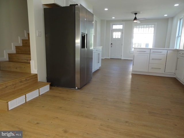 kitchen featuring light wood-type flooring, light countertops, white cabinets, and stainless steel refrigerator with ice dispenser