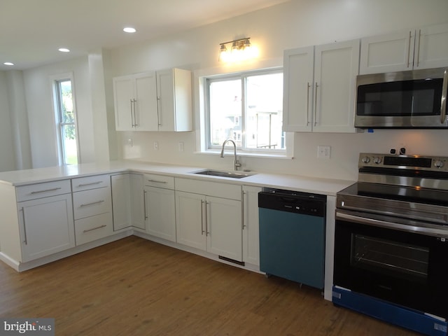 kitchen with white cabinets, a peninsula, stainless steel appliances, and light countertops