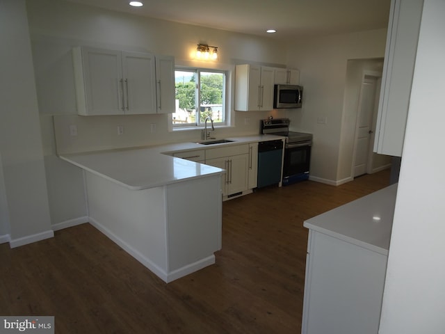 kitchen featuring dark wood finished floors, appliances with stainless steel finishes, light countertops, white cabinetry, and a sink