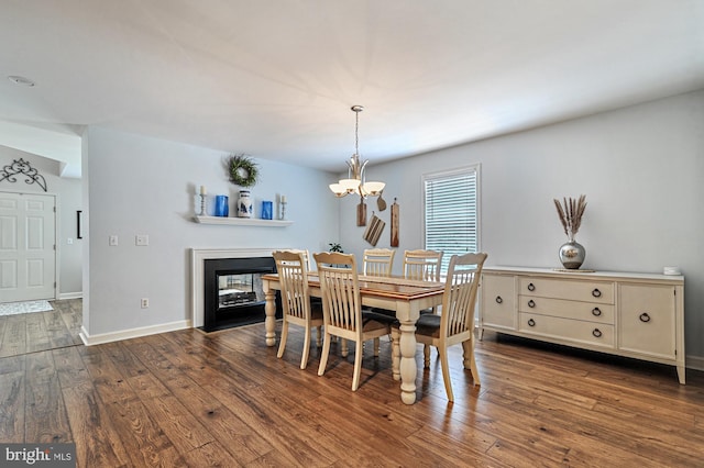 dining space with a multi sided fireplace, dark hardwood / wood-style flooring, and a chandelier