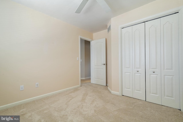 unfurnished bedroom featuring ceiling fan, light colored carpet, and a closet