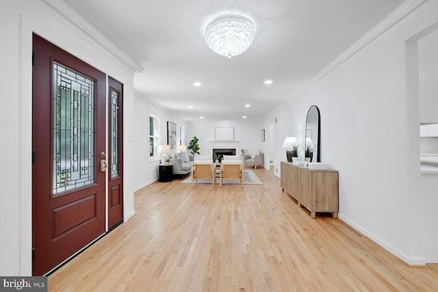 entryway featuring light hardwood / wood-style floors, crown molding, and an inviting chandelier