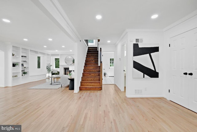 foyer entrance with ornamental molding and light hardwood / wood-style floors