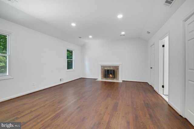 unfurnished living room featuring a brick fireplace, a wealth of natural light, and lofted ceiling