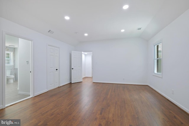 unfurnished bedroom featuring ensuite bathroom, vaulted ceiling, and dark hardwood / wood-style flooring