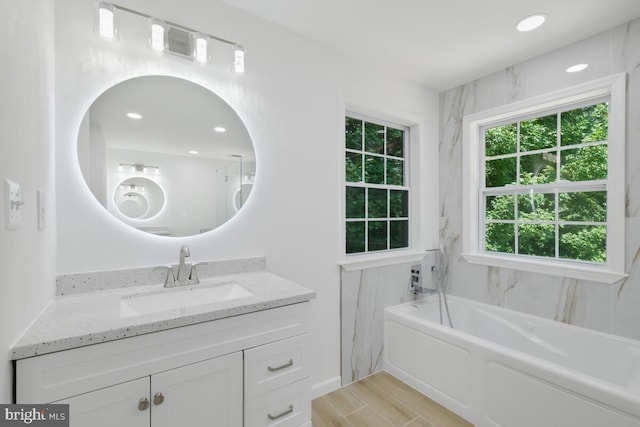 bathroom featuring a bath, plenty of natural light, and vanity