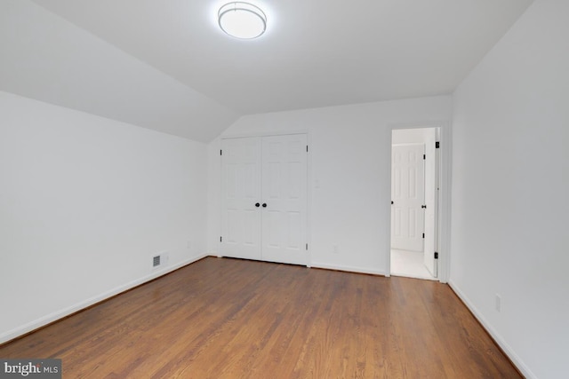 additional living space with vaulted ceiling and dark hardwood / wood-style floors