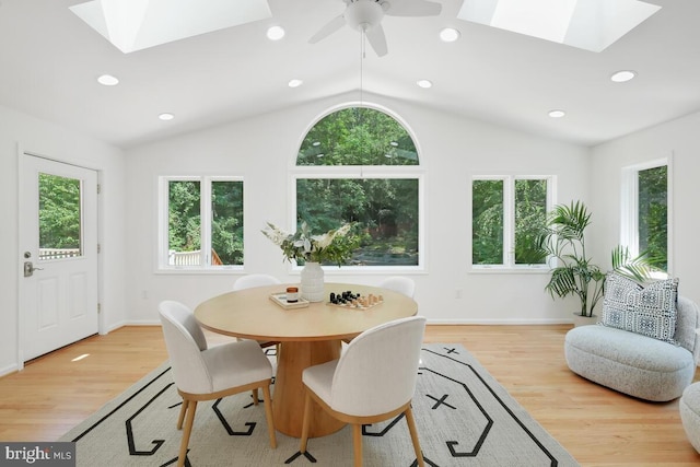 dining area with light wood-type flooring, ceiling fan, and lofted ceiling with skylight