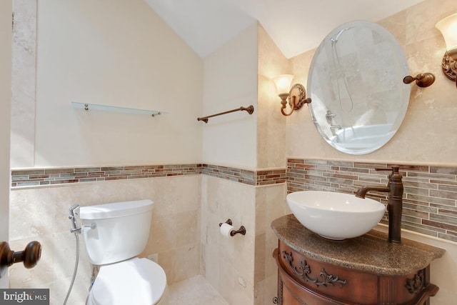 bathroom featuring toilet, tile walls, vaulted ceiling, and vanity