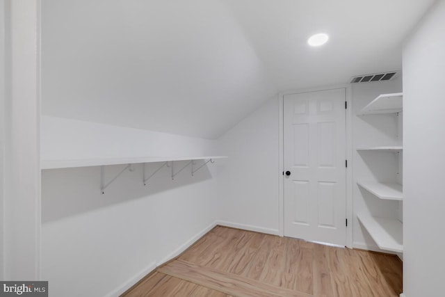 walk in closet featuring light hardwood / wood-style flooring and lofted ceiling