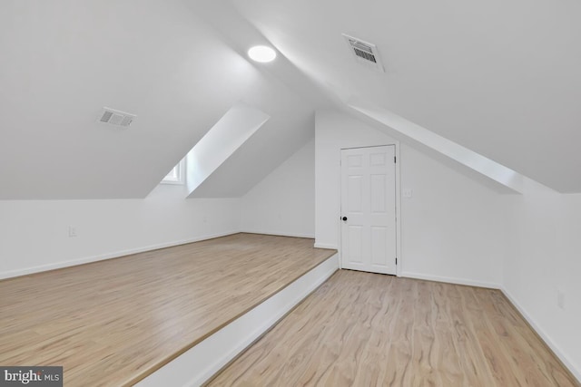 bonus room with light wood-type flooring and vaulted ceiling with skylight