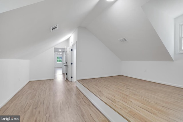 additional living space featuring light wood-type flooring and lofted ceiling