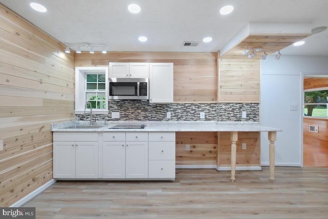 kitchen with light hardwood / wood-style floors, sink, white cabinetry, light stone countertops, and track lighting