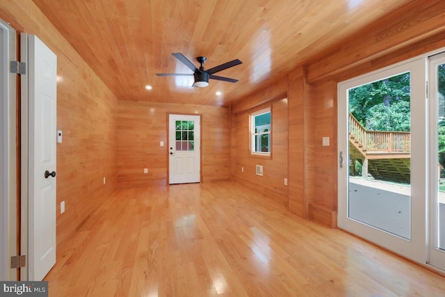 spare room featuring ceiling fan, wooden ceiling, light hardwood / wood-style flooring, and wood walls