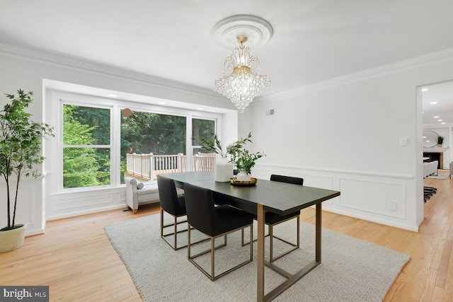 dining area featuring an inviting chandelier, crown molding, and light hardwood / wood-style flooring