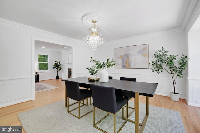 dining room with ornamental molding, light hardwood / wood-style flooring, and a notable chandelier