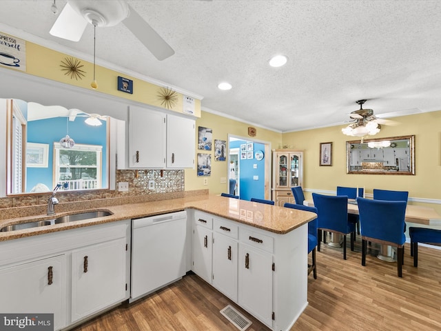 kitchen featuring kitchen peninsula, white cabinets, sink, and white dishwasher