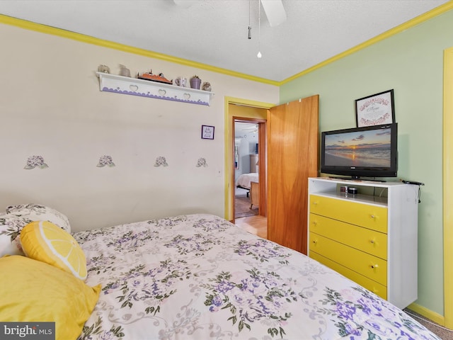 bedroom with ceiling fan, a textured ceiling, and ornamental molding