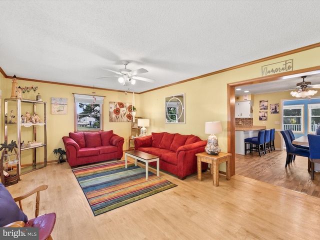 living room with hardwood / wood-style flooring, crown molding, a textured ceiling, and ceiling fan