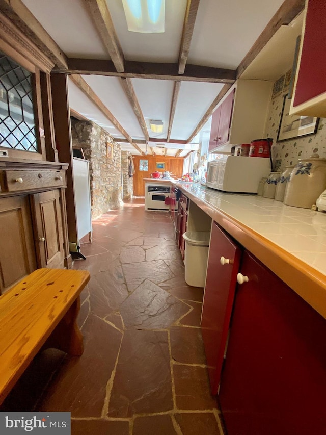 kitchen with beamed ceiling, oven, and tile countertops