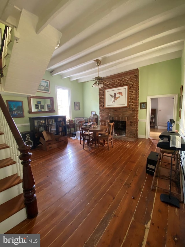 living room featuring beamed ceiling, dark hardwood / wood-style floors, a fireplace, and ceiling fan