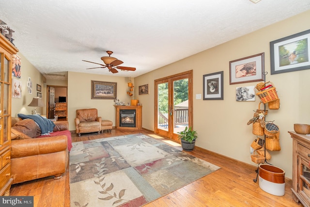 living room featuring french doors, a textured ceiling, light hardwood / wood-style flooring, and ceiling fan