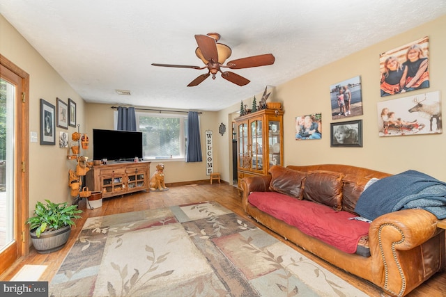 living room featuring light wood-type flooring, ceiling fan, and a healthy amount of sunlight