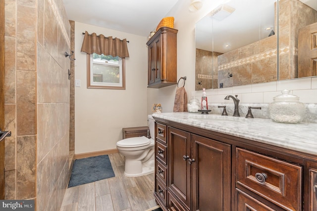 bathroom featuring hardwood / wood-style floors, tile walls, decorative backsplash, toilet, and vanity