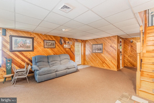 carpeted living room featuring wooden walls and a paneled ceiling