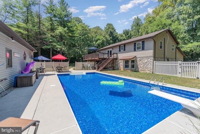 view of swimming pool featuring a deck, a patio, and a diving board