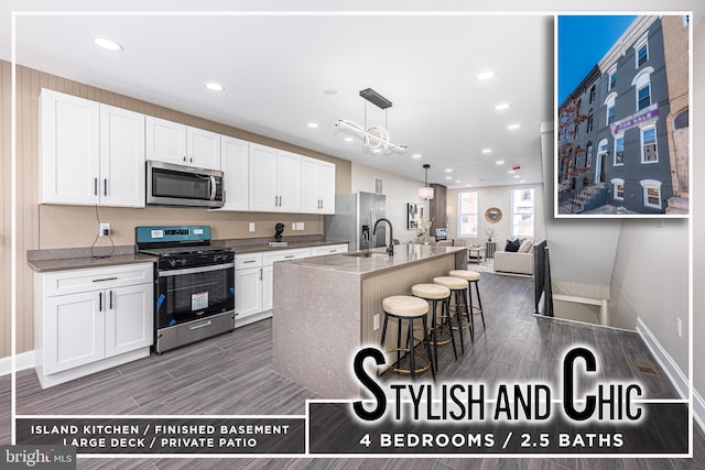 kitchen with a kitchen breakfast bar, an island with sink, pendant lighting, white cabinets, and appliances with stainless steel finishes