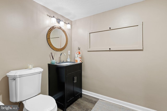 bathroom with toilet, vanity, and hardwood / wood-style flooring